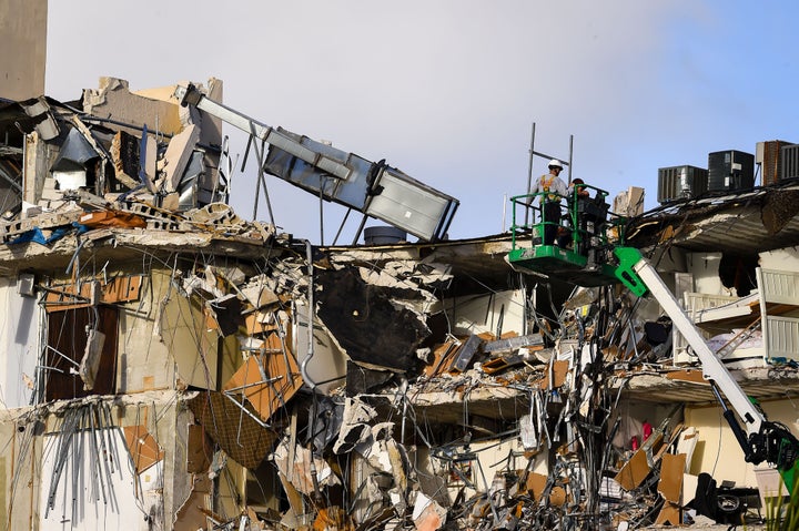 Rescue workers on a crane stand above the wreckage of a partially collapsed building in Surfside north of Miami Beach, Florida on June 25, 2021. (Photo by Eva Marie UZCATEGUI / AFP) (Photo by EVA MARIE UZCATEGUI/AFP via Getty Images)