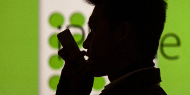 A man uses his phone as he walks past an Apple store in Hong Kong on December 25, 2013, on Christmas day. Apple shares rose on December 23 after the company sealed a hard-won deal with China Mobile which will see the world's biggest wireless operator make the iPhone widely available to customers. AFP PHOTO / ANTHONY WALLACE (Photo credit should read ANTHONY WALLACE/AFP/Getty Images)