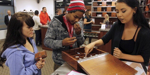 Morgan McKee (R) helps Juliano Hamana (C) and Jayme Jennings (L) browse samples at Shango Cannabis shop on first day of legal recreational marijuana sales beginning at midnight in Portland, Oregon October 1, 2015. The sale of marijuana for recreational use began in Oregon on October 1, 2015 as it joined Washington state and Colorado in allowing the sale of a drug that remains illegal under U.S. federal law. REUTERS/Steve Dipaola