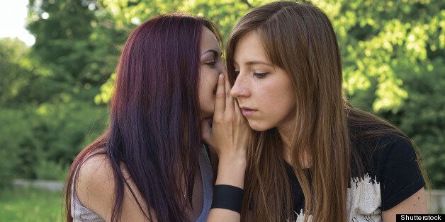 two young girls are whispering