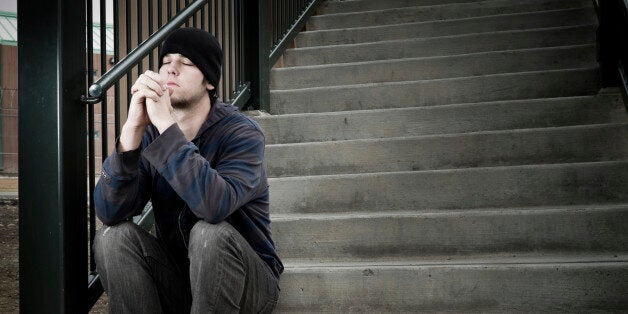 Young man in a sad and desperate emotional state with hands folded in prayer