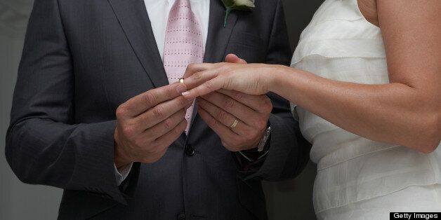 Groom putting ring on brides finger