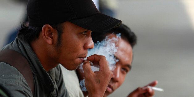 Men smoke cigarettes at railway station in Jakarta May 24, 2012. Anti-tobacco advocates in Indonesia plan to file a class action lawsuit this month using cases of child addicts in the hope of forcing tougher regulations on a society where one in three people smokes. The suit against tobacco companies and the Indonesian government argues that feeble regulation has left children dangerously exposed to the risks of smoking. Indonesia is something of a paradise for both smokers and tobacco companies, with the world's fifth largest population of smokers. It is a widely tolerated habit and one which even in this relatively poor archipelago most can afford to feed. To match Feature INDONESIA-SMOKING/ REUTERS/Beawiharta (INDONESIA - Tags: POLITICS SOCIETY)