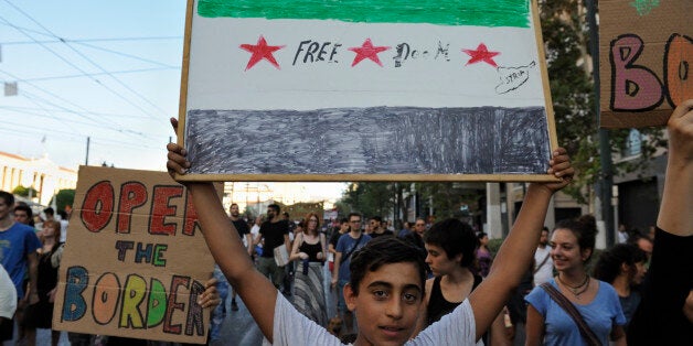 ATHENS, GREECE - AUGUST 29: A refugee child holds a placard depicting a Syrian flag with the words 'Freedom Syria' in central Athens during the protest against the August 24th, 2016 arson attack on the refugee housing squat in Notara street at the port of Piraeus on August 29, 2016 in Athens, Greece. (Photo by Nicolas Koutsokostas/Corbis via Getty Images)