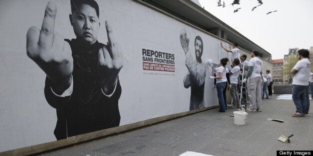 Activists of the international non-governmental organization 'Reporters sans frontieres' (Reporters without borders) set on a wall posters bearing pictures of Iranian President Mahmoud Ahmadinejad (R) and North Korea leader Kim Jong-Un in Paris, on May 03, 2013, as they launch a campaign marking world press freedom day. The posters bear pictures of chief of states qualified by the organization as 'predators of Freedom of Information' gesturing angrily. AFP PHOTO KENZO TRIBOUILLARD (Photo credit should read KENZO TRIBOUILLARD/AFP/Getty Images)