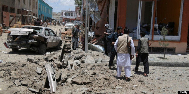 Afghan officials and bystanders are pictured at the site of a roadside bomb blast in Ghazni province on July 3, 2013. The blast which occured near a girls' school wounded six civilians including a woman and a child, local officials said. AFP PHOTO/ Rahmatullah ALIZAD (Photo credit should read Rahmatullah Alizad/AFP/Getty Images)