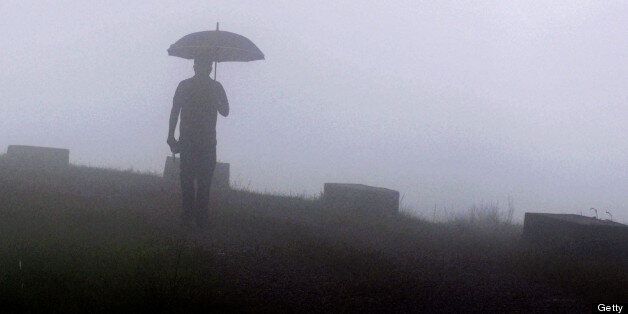 TO GO WITH India-climate-travel-nature-rain-Guinness,FEATURE by Ammu Kannampilly In this photograph taken on June 21, 2013, an Indian pedestrian walks through heavy fog at Mawsynram village in the north-eastern Indian state of Meghalaya and considered the 'wettest place on earth' according to the Guinness World Records authority. Deep in India's northeast, villagers use grass to sound-proof their huts from deafening rain, clouds are a familiar sight inside homes and a suitably rusted sign tells visitors they are in the 'wettest place on earth AFP PHOTO / BIJU BORO (Photo credit should read BIJU BORO/AFP/Getty Images)