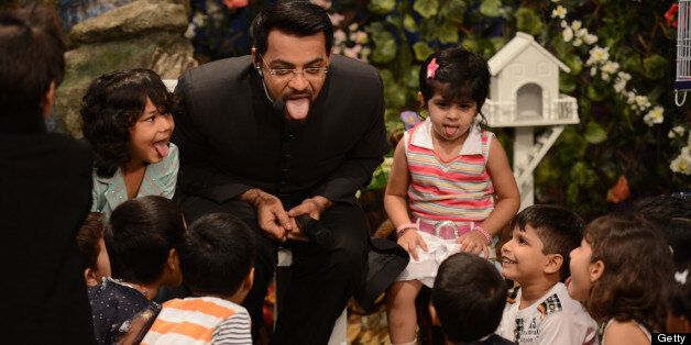 TO GO WITH 'PAKISTAN-RELIGION-MEDIA-ISLAM-RAMADAN-TELEVISION' by Guillaume LAVALLÉE In this photograph taken on July 31, 2013, Pakistani television show host Aamir Liaqat Hussain play with youngsters during a segment for children in a Islamic quiz show for Ramadan in Karachi. A charismatic Muslim preacher criticised for giving out babies to childless couples live on prime-time Pakistani television denies he is crudely seeking top ratings and insists he is spreading charity. Aamir Liaqat Hussain, one of the biggest stars on Pakistani TV, spoke to AFP as a charity involved in the process said a third baby is due to be given away in the coming days. Hussain broadcasts a marathon 12-hour show each day during the holy month of Ramadan, watched by millions of viewers across the country. AFP PHOTO / ASIF HASSAN (Photo credit should read ASIF HASSAN/AFP/Getty Images)
