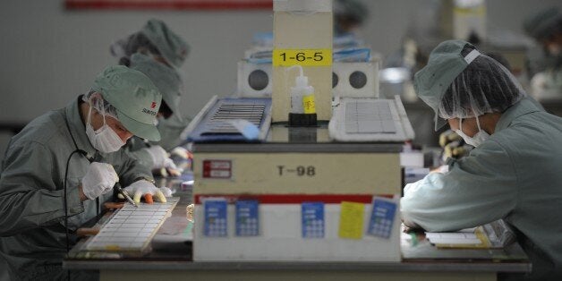 TO GO WITH: China-US-energy-solar-trade,FOCUS by Bill SavadoveThis picture taken on February 27, 2012 shows workers assembling solar panels by hand on the factory floor of Chinese company Suntech in the eastern Chinese city of Wuxi. The success of Chinese companies like Suntech, the world's biggest producer of solar panels has become a trade issue as American companies accuse them of dumping in the US market and receiving unfair subsidies from Beijing. AFP PHOTO/Peter PARKS (Photo credit should read PETER PARKS/AFP/Getty Images)