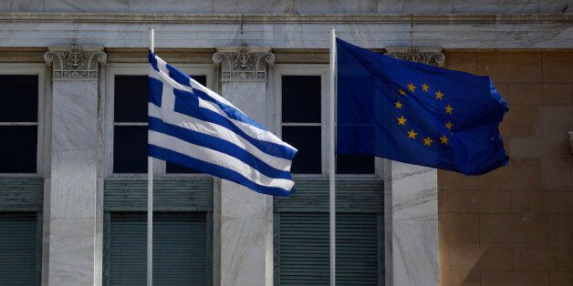 A Greek national flag, left, flies beside a European Union (EU) flag in Athens, Greece, on Monday, March 31, 2014. The European Commission predicts the Greek economy will grow in 2014 for the first time in seven years, and the nation is now looking to start selling debt again next month after achieving a budget surplus last year. Photographer: Kostas Tsironis/Bloomberg via Getty Images