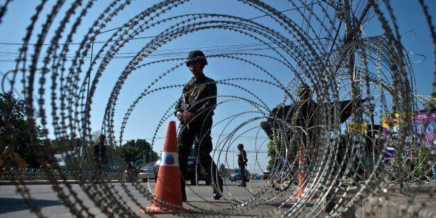 Thai soldiers stand guard at a checkpoint near the pro-government ''Red shirts'' camp site on the outskirts of Bangkok on May 22, 2014. Thailand's military hosted ground-breaking talks on May 21 between warring political rivals after imposing martial law to prevent the deeply divided kingdom degenerating into another 'Ukraine or Egypt'. AFP PHOTO/ Manan VATSYAYANA (Photo credit should read MANAN VATSYAYANA/AFP/Getty Images)