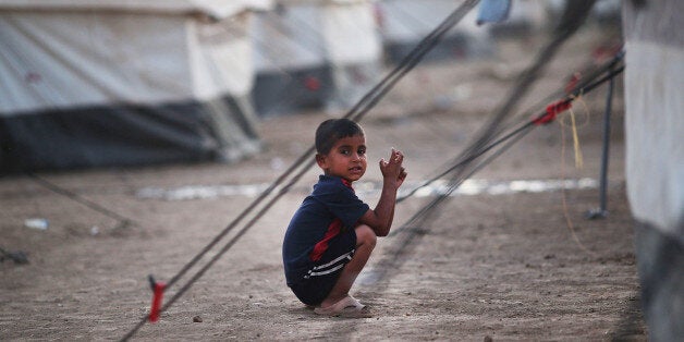 KALAK, IRAQ - JUNE 24: An Iraqi child pauses in a temporary displacement camp for Iraqis caught-up in the fighting in and around the city of Mosul on June 24, 2014 in Kalak, Iraq.Tens of thousands of people have fled Iraq's second largest city of Mosul after it was overrun by ISIS (Islamic State of Iraq and Syria) militants. Many have been temporarily housed at various IDP (internally displaced persons) camps around the region including the area close to Erbil, as they hope to enter the safety of the nearby Kurdish region. (Photo by Spencer Platt/Getty Images)