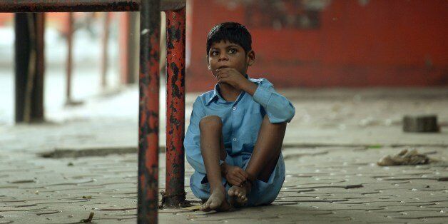 To go with story 'India-disabled-rights-poverty' by Rachel O'BrienIn this photograph taken on May 20, 2014 nine year old Indian boy Lakhan Kale is tied with a cloth rope around his ankle, to a bus-stop pole in Mumbai. The nine-year-old boy dressed in blue lay listlessly on the pavement in the scorching Mumbai summer afternoon, his ankle tethered with rope to a bus stop, unheeded by pedestrians strolling past. Lakhan Kale cannot hear or speak and suffers from cerebral palsy and epilepsy, so his grandmother and carer tied him up to keep him safe while she went to work, selling toys and flower garlands on the city's roadsides. AFP PHOTO/ PUNIT PARANJPE (Photo credit should read PUNIT PARANJPE/AFP/Getty Images)