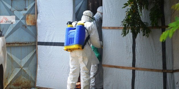 A picture taken on June 28, 2014 shows Red Cross staff preparing a body for burial at the isolation ward of the Donka Hospital in Conakry, where people infected with the Ebola virus are being treated. The World Health Organization has warned that Ebola could spread beyond hard-hit Guinea, Liberia and Sierra Leone to neighbouring nations, but insisted that travel bans were not the answer. To date, there have been 635 cases of haemorrhagic fever in Guinea, Liberia and Sierra Leone, most confirmed as Ebola. A total of 399 people have died, 280 of them in Guinea. AFP PHOTO / CELLOU BINANI (Photo credit should read CELLOU BINANI/AFP/Getty Images)