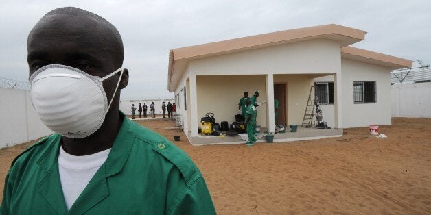 A man, wearing a protective mask, poses in front of an isolation center for people suffering from the Ebola virus, on August 12, 2014 at the airport in Abidjan. The Ivory Coast announced on the eve that it has banned all flights from countries hit by Ebola as part of steps to prevent the deadly virus from reaching the west African nation. AFP PHOTO/ SIA KAMBOU (Photo credit should read SIA KAMBOU/AFP/Getty Images)