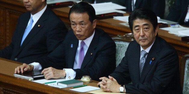 Shinzo Abe, Japan's prime minister, right, Taro Aso, deputy prime minister and minister for finance and financial services, center, and Akira Amari, Japan's economic revitalization minister, attend an extraordinary session at the lower houses of the parliament in Tokyo, Japan, on Monday, Sept. 29, 2014. Abe said in his speech at the opening of the parliamentary session, he must carefully watch the effect on economy of sales-tax increase, fuel price rises and bad weather. Photographer: Tomohiro Ohsumi/Bloomberg via Getty Images 