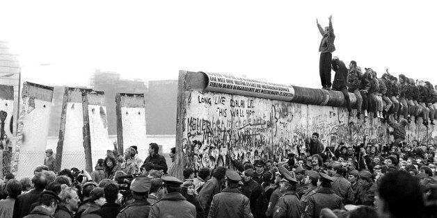 BERLIN - CIRCA NOVEMBER 1989: People gather near a part of the Berlin Wall that has been broken down after the communist Ger