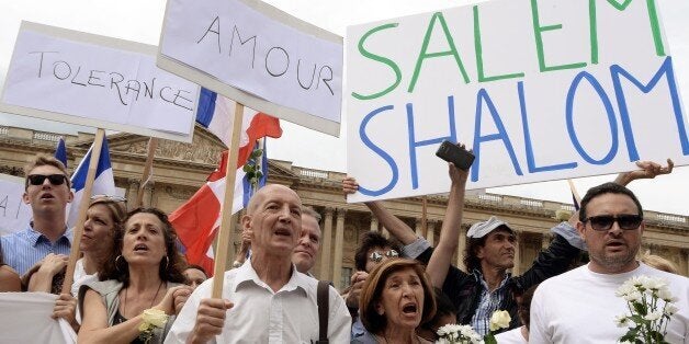 Demonstrators hold French national flags and boards reading messages of peace on August 3, 2014 in front of the Saint-Germain L'Auxerrois church in Paris as they take part in a demonstration originally called by a student on Facebook, and gathering Jews and Moslems to advocate peace and fraternity in the context of the Israeli offensive in Gaza. The signs read (from L) 'Tolerance', 'Love' and 'Salem Shalom'. AFP PHOTO / PIERRE ANDRIEU (Photo credit should read PIERRE ANDRIEU/AFP/Getty Images)