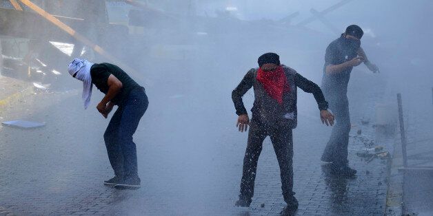 Left-wing protesters try to avoid tear gas and water used by police to disperse them, in Istanbul, Sunday, July 26, 2015, during clashes between police and people protesting against Turkey's operation against Kurdish militants. Turkey has bombed Islamic State positions near the Turkish border in Syria, also targeting Kurdish rebels in Iraq and carried out widespread police operations against suspected Kurdish and IS militants and other outlawed groups inside Turkey. (AP Photo/Cagdas Erdogan) TURKEY OUT