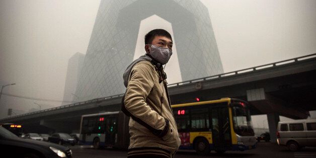 BEIJING, CHINA - NOVEMBER 29: A Chinese man wears a mask as he waits to cross the road near the CCTV building during heavy smog on November 29, 2014 in Beijing, China. United States President Barack Obama and China's president Xi Jinping agreed on a plan to limit carbon emissions by their countries, which are the world's two biggest polluters, at a summit in Beijing earlier this month. (Photo by Kevin Frayer/Getty Images)