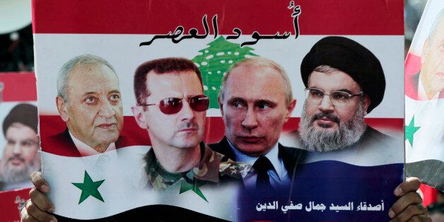 A Syrian who lives in Lebanon holds a poster with photos of Lebanese Parliament Speaker Nabih Berri, left, Syrian President Bashar Assad, second left, Russian President Vladimir Putin, second right, Hezbollah leader Sheikh Hassan Nasrallah, right with Arabic that reads "Lions of the time," during a rally to thank Moscow for its intervention in Syria, in front of the Russian embassy in Beirut, Lebanon, Sunday, Oct. 18, 2015. (AP Photo/Bilal Hussein)
