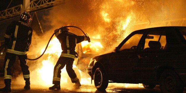 FILE - In this Nov. 8, 2005 file photo, firefighters work to extinguish burning cars set on fire by rioters in Gentilly, south of Paris, France. Two young boys were electrocuted in a power substation in Clichy-sous-Bois, while hiding from police on Oct. 27, 2005. A court in western France rules on whether two police officers contributed to the deaths of two teens in 2005, in an accident that sparked three weeks of national riots by largely minority youth angry at bleak job prospects and entrenched discrimination. Tensions between housing project youths and France's largely white police force haven't abated 10 years later. The boys' families and neighbors want the police held unaccountable, but even prosecutors say they don't have enough evidence and requested acquittal. (AP Photo/Michel Spingler, File)