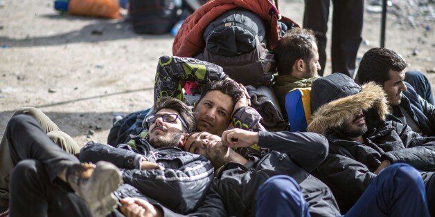 Migrants and refugees lie on the ground as they wait to enter a registration camp after crossing the Greek-Macedonian border near Gevgelija on November 11, 2015. European leaders tried to focus on joint action with Africa to tackle the migration crisis, as Slovenia became the latest EU member to act on its own by barricading its border. AFP PHOTO / ROBERT ATANASOVSKI (Photo credit should read ROBERT ATANASOVSKI/AFP/Getty Images)