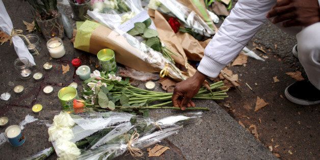 PARIS, FRANCE - NOVEMBER 14: People place flowers on the pavement near the scene of yesterday's Bataclan Theatre terrorist attack on November 14, 2015 in Paris, France. At least 120 people have been killed and over 200 injured, 80 of which seriously, following a series of terrorist attacks in the French capital. (Photo by Christopher Furlong/Getty Images)