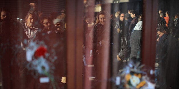 PARIS, FRANCE - NOVEMBER 15: People are reflected in the windows of Le Carillon restaurant as they read tributes on November 15, 2015 in Paris, France. As France observes three days of national mourning members of the public continue to pay tribute to the victims of Friday's deadly attacks. A special service for the families of the victims and survivors is to be held at Paris's Notre Dame Cathedral later on Sunday. (Photo by Christopher Furlong/Getty Images)