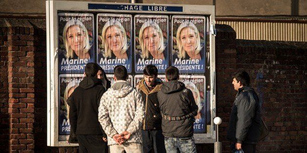 Migrant men stand in front of electoral posters of French far-right National Front (FN) party President Marine Le Pen in Calais on December 7, 2015.France's far-right National Front saw record-high results in the first round of regional polls on December 6, held under a state of emergency just three weeks after Islamic extremists killed 130 people in Paris. / AFP / PHILIPPE HUGUEN (Photo credit should read PHILIPPE HUGUEN/AFP/Getty Images)