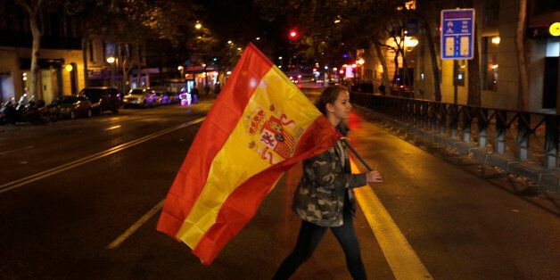 A supporter of the Popular Party carries a Spanish flag as she leaves the party headquarters in Madrid, Sunday, Dec. 20, 2015. A strong showing Sunday by a pair of upstart parties in Spain's general election upended the country's traditional two-party system, with the ruling Popular Party winning the most votes but falling far short of a parliamentary majority and at risk of being booted from power.(AP Photo/Emilio Morenatti)