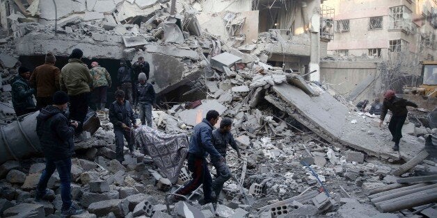 Syrians and civil defence workers evacuate victims from the rubble of a destroyed building following air strikes on the Eastern Ghouta town of Douma, a rebel stronghold east of the capital Damascus, on January 10, 2016. / AFP / SAMEER AL-DOUMY (Photo credit should read SAMEER AL-DOUMY/AFP/Getty Images)