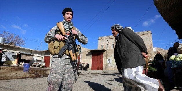 TO GO WITH AFP STORY BY JONATHAN KROHN Brett (C), a 28-year-old US national who fights jihadists of the Islamic State (IS) group alongside Dwekh Nawsha, a Christian militia whose name is an Assyrian-language phrase conveying self-sacrifice, patrols a street on February 5, 2015, in the northern Iraqi town of Al-Qosh, located 35 km north of Mosul. The foreign contingent fighting IS is tiny compared to the thousands of foreigners who have joined the jihadist group, but interest is growing and 20 more volunteers already lined up to join. AFP PHOTO / SAFIN HAMED (Photo credit should read SAFIN HAMED/AFP/Getty Images)