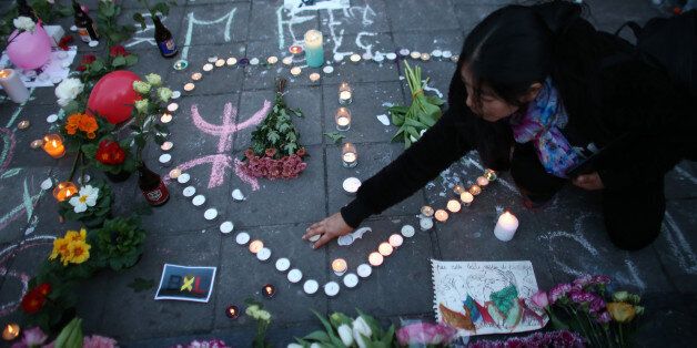 BRUSSELS, BELGIUM - MARCH 22: A woman lights a candle as people gather to leave tributes at the Place de la Bourse following today's attacks on March 22, 2016 in Brussels, Belgium. At least 31 people are thought to have been killed after Brussels airport and a Metro station were targeted by explosions. The attacks come just days after a key suspect in the Paris attacks, Salah Abdeslam, was captured in Brussels. (Photo by Carl Court/Getty Images)