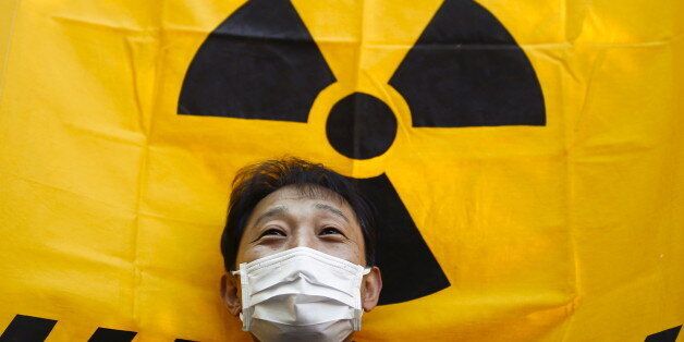 A man holds a flag with a radioactive hazard symbol during No Nukes Day, a protest calling for a nuclear-free future, in Yoyogi park in Tokyo, Japan, March 26, 2016. REUTERS/Thomas Peter