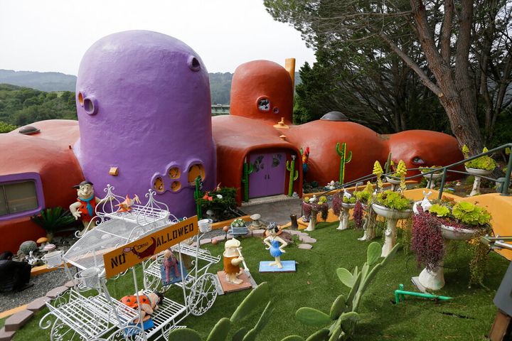 The Flintstone House is seen before a news conference with the owner and the home's original architect in Hillsborough, Calif. The San Francisco Bay Area suburb of Hillsborough is suing the owner of the house, saying that she installed dangerous steps, dinosaurs and other Flintstone-era figurines without necessary permits. In a yabba dabba dispute that pitted property rights against government rules that played out in international media, retired publishing mogul Florence Fang defended her colorful, bulbous-shaped house and its elaborate homage to "The Flintstones" family, featuring Stone Age sculptures inspired by the 1960s cartoon, along with aliens and other oddities. (AP Photo/Eric Risberg, File)