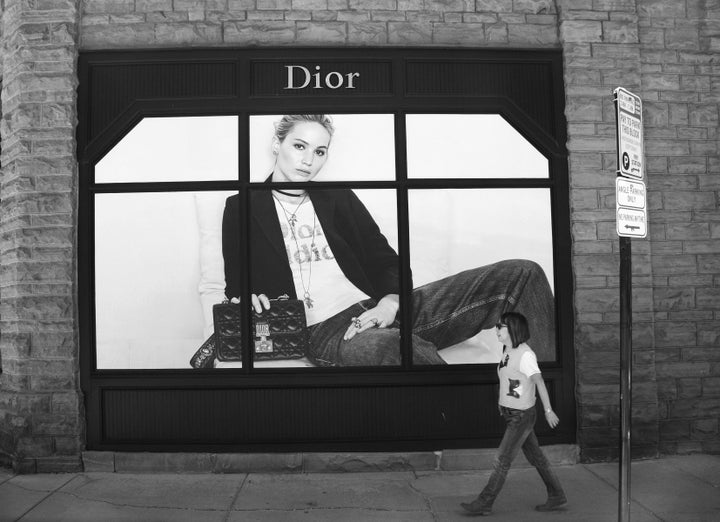 A tourist walks past a window display featuring a photograph of actress Jennifer Lawrence at a Dior store in Aspen, Colorado.