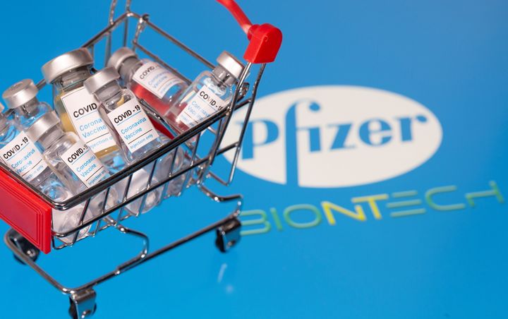 A small shopping basket filled with vials labeled "COVID-19 - Coronavirus Vaccine" is placed on a Pfizer logo in this illustration taken November 29, 2020. Picture taken November 29, 2020. REUTERS/Dado Ruvic/Ilustration