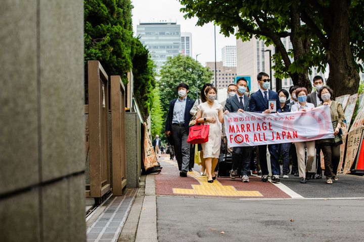 1月に亡くなった佐藤郁夫さんの遺影とともに入廷する原告ら＝2021年6月30日撮影