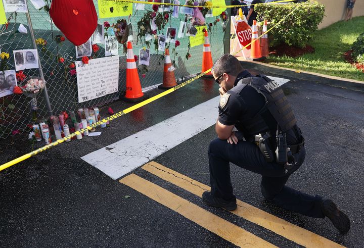Miami Beach Police Officer David Cajuso prays before a memorial set up near the partially collapsed 12-story building on Wednesday.