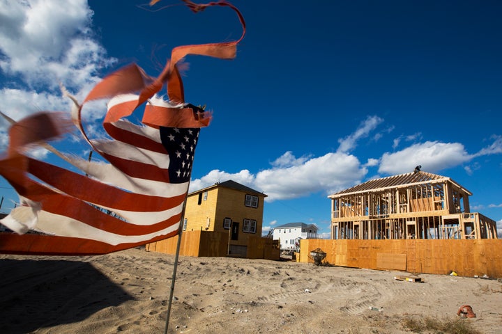 A tattered U.S. flag waves in the wind as construction workers build new homes in an area of Breezy Point in Queens, New York.