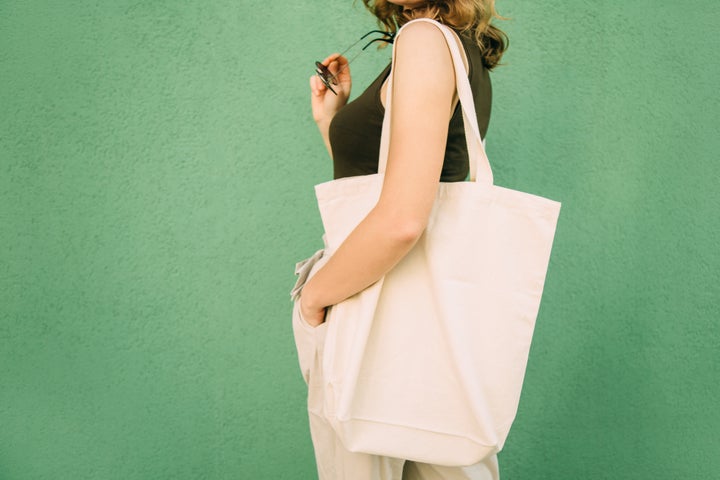 Beautiful blonde girl with eco bag over green background