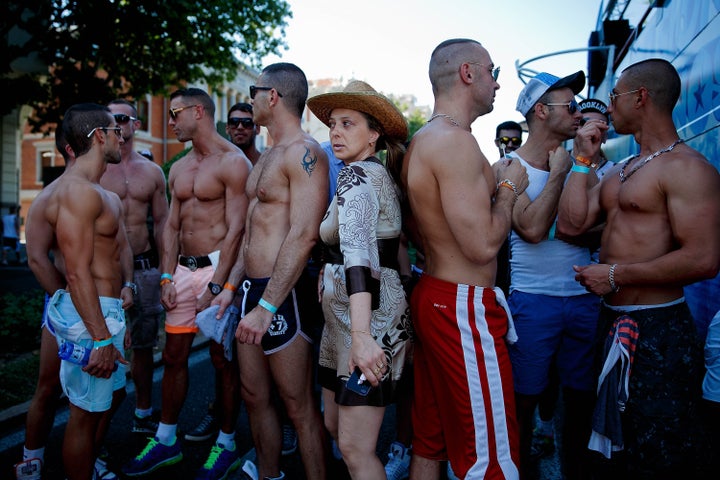 Mujer pasando entre grupo de hombres gais en el desfile del Orgullo en 2013.