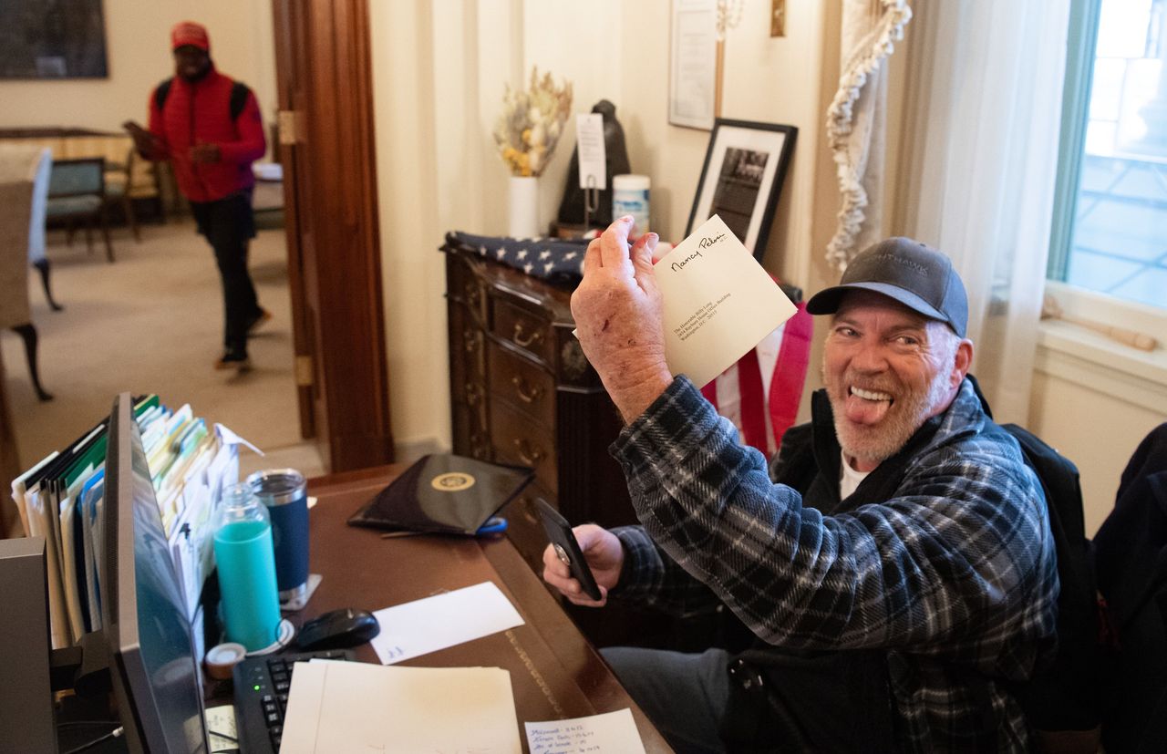 Richard Barnett, a supporter of President Donald Trump, holds a piece of mail as he sits inside the office of House Speaker Nancy Pelosi (D-Calif.) after insurrectionists breached the U.S. Capitol on Jan. 6.
