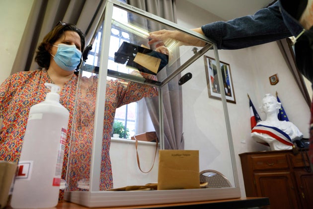 Un électeur dépose son bulletin de vote dans un bureau de vote de la mairie d'Etaples, dans le nord de la France, pour le second tour des élections régionales, le 27 juin 2021. (Photo by LUDOVIC MARIN/AFP via Getty Images)