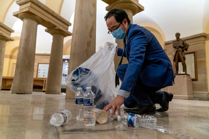 Rep. Andy Kim, D-N.J., cleans up debris and trash strewn across the floor in the early morning hours of Jan. 7, 2021, after protesters stormed the Capitol in Washington.