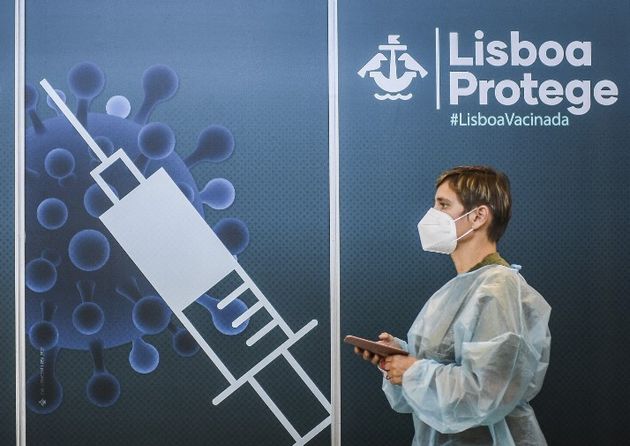 Un soignant passe devant le poster d'un centre de vaccination à Lisbonne, le 2 juillet