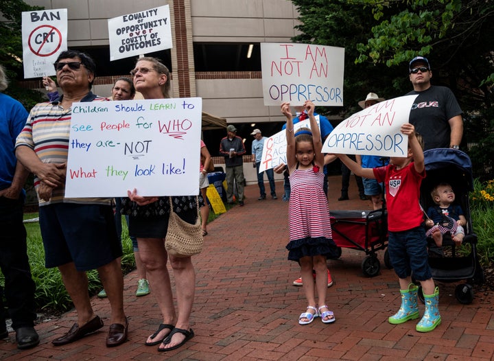 People hold up signs during a rally against "critical race theory" (CRT) being taught in schools at the Loudoun County Government center in Leesburg, Virginia on June 12, 2021. - "Are you ready to take back our schools?" Republican activist Patti Menders shouted at a rally opposing anti-racism teaching that critics like her say trains white children to see themselves as "oppressors." "Yes!", answered in unison the hundreds of demonstrators gathered this weekend near Washington to fight against "critical race theory," the latest battleground of America's ongoing culture wars. The term "critical race theory" defines a strand of thought that appeared in American law schools in the late 1970s and which looks at racism as a system, enabled by laws and institutions, rather than at the level of individual prejudices. But critics use it as a catch-all phrase that attacks teachers' efforts to confront dark episodes in American history, including slavery and segregation, as well as to tackle racist stereotypes. (Photo by ANDREW CABALLERO-REYNOLDS / AFP) (Photo by ANDREW CABALLERO-REYNOLDS/AFP via Getty Images)