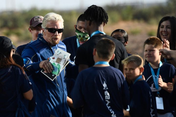 Richard Branson(L) receives some cards from children as he walks out from Spaceport America, near Truth and Consequences, New Mexico on July 11, 2021 before travel to the cosmos. - He's always dreamed of it, and in 2004 founded his own company to make it happen. On July 11, 2021, billionaire Richard Branson will take off from a base in New Mexico aboard a Virgin Galactic vessel bound for the edge of space. The Briton is hoping to finally get the nascent space tourism industry off the ground -- but also go one up on Jeff Bezos by winning the race to be the first person to cross the final frontier in a ship built by their own company.The Amazon founder's great rival, SpaceX boss Elon Musk, announced on Twitter he'd be there to witness it. (Photo by Patrick T. FALLON / AFP) (Photo by PATRICK T. FALLON/AFP via Getty Images)
