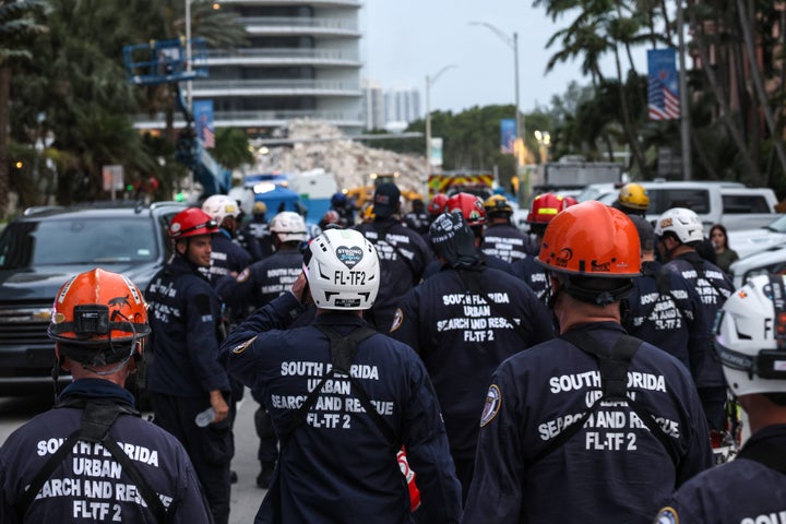 Search and rescue personnel walk back to work on the recovery operation at the collapsed 12-story Champlain Towers South cond